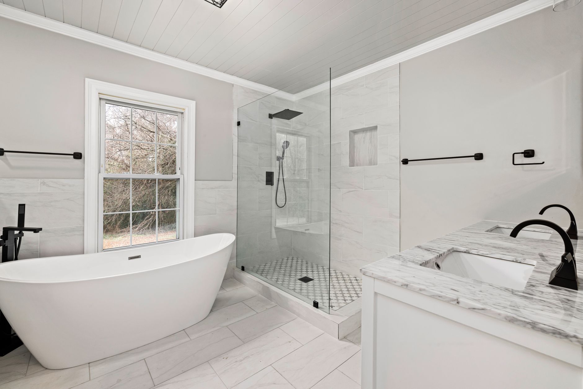 Sleek bathroom featuring a freestanding tub, glass shower, and marble accents in Lakewood, CA